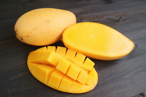 Closeup Fresh Ripe Juicy Mango Cut in Half and Crosswise Cut with a Whole Fruit in the Backdrop